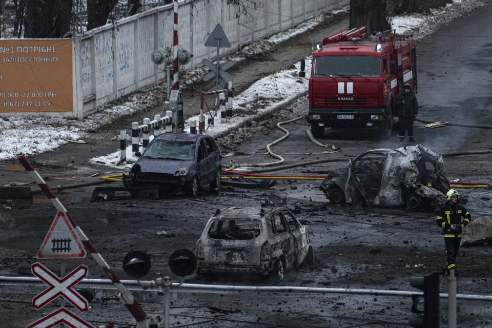 A firefighter walks in front of destroyed cars after Russian rocket attack in Kyiv, Ukraine, Wednesday, Nov. 23, 2022. (AP Photo/Evgeniy Maloletka)