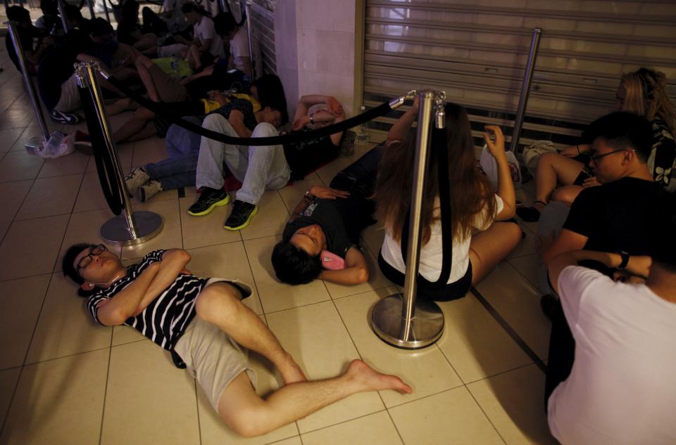 People sleep as they queue overnight for the launch of the new Apple iPhone 6s mobile phone at a mall in Singapore