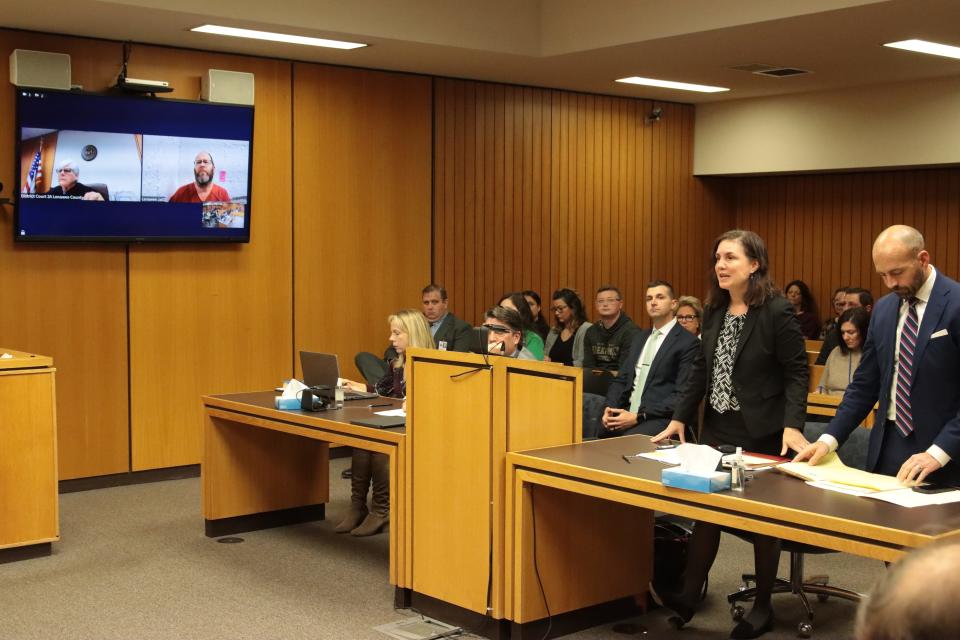 Mary Chartier, second from right, one of defendant Dale Warner's attorneys, addresses the court during a hearing on Warner's bond Monday in Lenawee County District Court. Also pictured are District Judge Laura J. Schaedler, left in the monitor; Warner, right in the monitor, and Shawn Head, Warner's other attorney, standing at right.