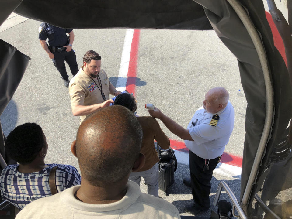 A passenger gets her temperature taken as she leaves an Emirates airplane at New York's Kennedy Airport amid reports of ill passengers aboard a flight from Dubai on Wednesday, Sept. 5, 2018. (Larry Coben via AP)