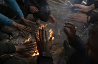 Bracing against harsh winter weather inside an abandoned hangar migrants warm their hands while gathered near the Hungarian border, outside of the village of Majdan, Serbia, Tuesday, Jan. 11, 2022. Hungary's nationalist prime minister, Viktor Orban, is keen to use the threat of migrants at his country's southern border to give him an advantage in upcoming elections. But the scale of migration pressure claimed by Orban is drawn into question by statistics from neighboring Serbia and the European Union's border agency. (AP Photo/Bela Szandelszky)