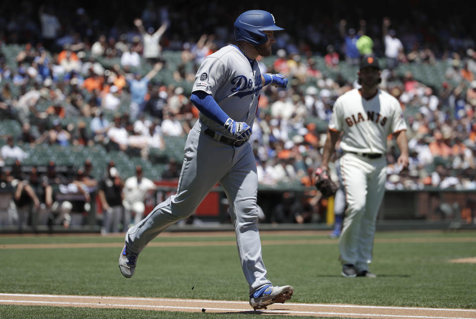 Los Angeles Dodgers' Max Muncy, left, gestures while running up the first base line after hitting a solo home run off of San Francisco Giants pitcher Madison Bumgarner, right, during the first inning of a baseball game in San Francisco, Sunday, June 9, 2019. (AP Photo/Jeff Chiu)