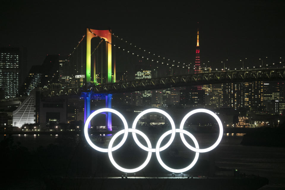 The illuminated Olympic rings float in the water as the Rainbow Bridge and the Tokyo Tower are visible in the distance Friday, Jan. 24, 2020, in the Odaiba district of Tokyo. Tokyo put on a flashy fireworks display on Friday to mark the 6-months-to-go milestone for this summer's Olympics. (AP Photo/Jae C. Hong)