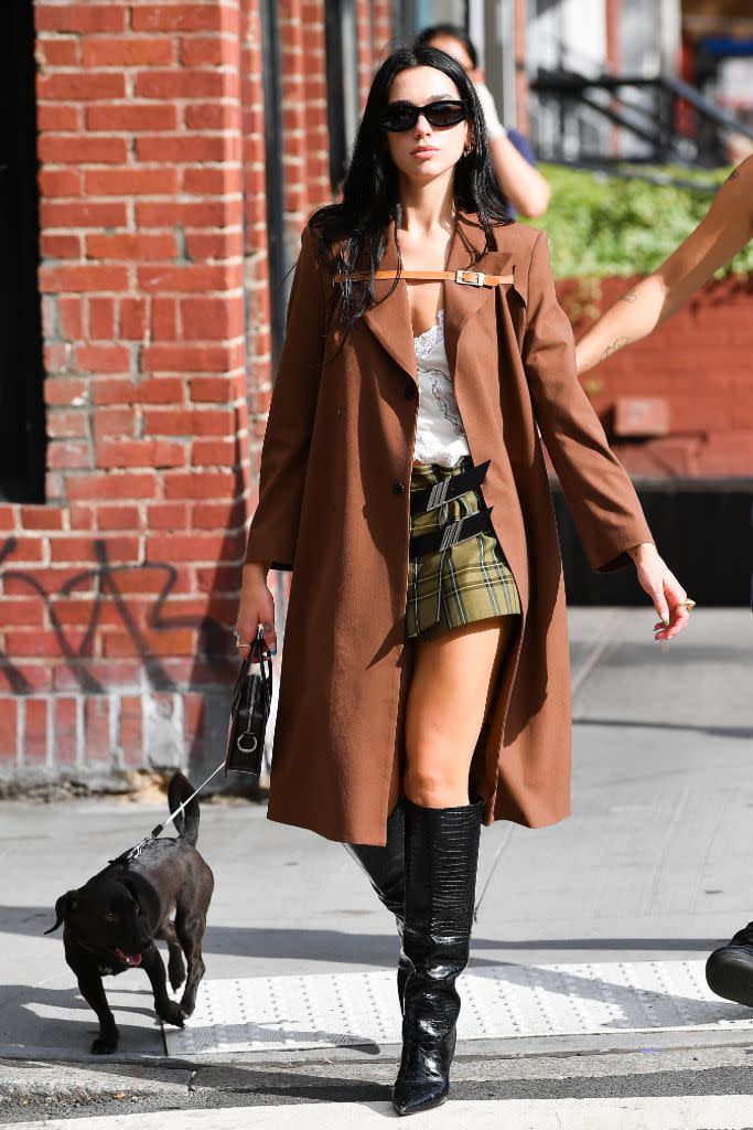 Dua Lipa in New York earlier this month, in a plaid mini skirt, knee-high black boots and a camel coat. - Credit: Splash