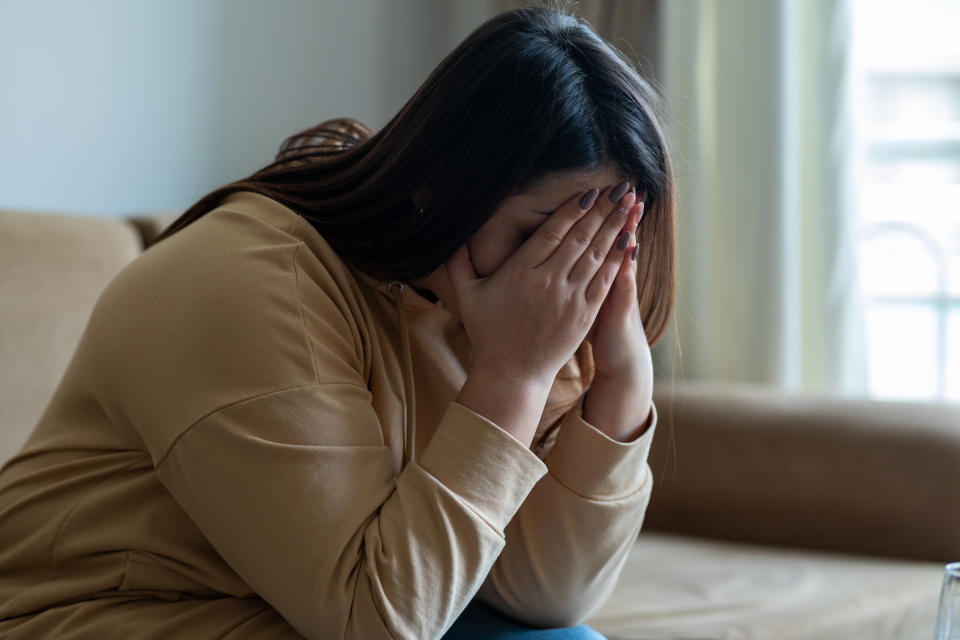 Sad woman sitting on a sofa in the living room. (Getty Images)