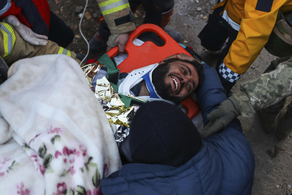 Rescatistas turcos llevan a Ergin Guzeloglan, de 36 años, a una ambulancia después de sacarlo de entre los escombros de un edificio derrumbado cinco días después de un terremoto, la madrugada del sábado 11 de febrero de 2023, en Hatay, en el sur de Turquía. (AP Foto/Can Ozer)