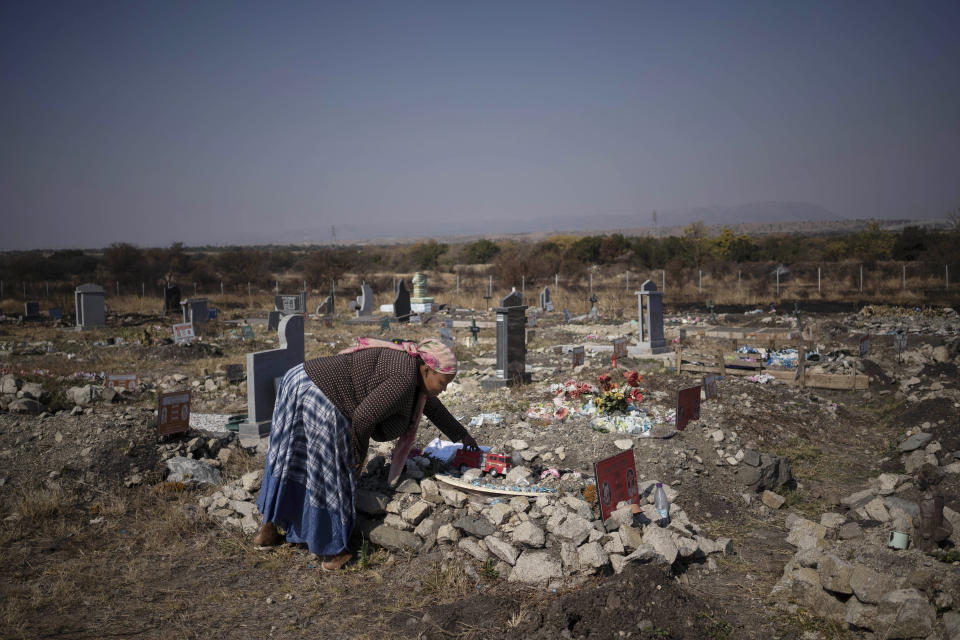 Rebecca Mohapi, who's son Onthatile died last year, puts one of his favorite toys on his grave in Damonsville, South Africa, on June 8, 2020. She believes her son's death wasn't an accident and that he was murdered. (AP Photo/Bram Janssen)