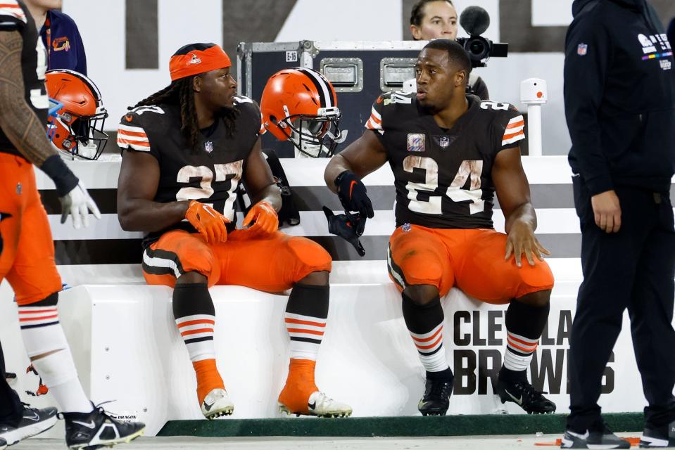 Browns running backs Nick Chubb (24) and Kareem Hunt (27) sit on the bench against the Bengals in Cleveland on Oct. 31, 2022.