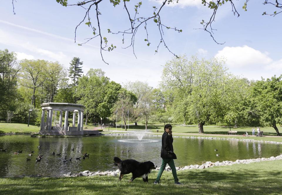 This May 17, 2013 photo shows Nancy Mah, of New York, and her dog Memphis walking in Congress Park in Saratoga Springs, N.Y. Saratoga Springs' racetrack is still going strong as it marks its 150th anniversary this summer, the centerpiece attraction in a town that's also known for mineral springs, Victorian charm and upscale hotels, shops and restaurants. (AP Photo/Mike Groll)