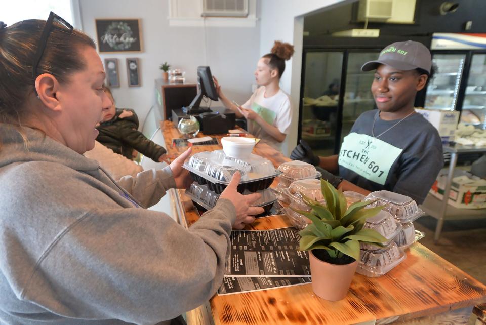 Customer Deana Williams, left, picks up an order from Diamond Mems, 17, at The Kitchen 601, near the intersection of Cherry Street and Brown Avenue, in Erie on April 10, 2024. Williams, a neonatal nurse practioner, was picking up lunch for colleagues in the NICU at UPMC Hamot.