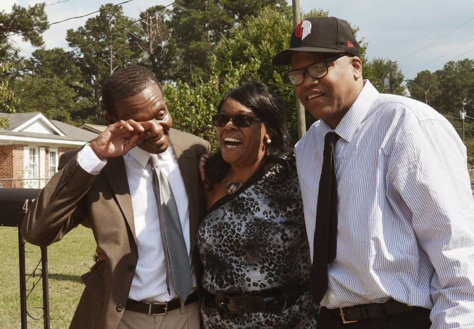 Geraldine Brown laughs as her brother Henry McCollum, left, wipes away tears as he and his brother Leon Brown, right, stand in her front yard in Fayetteville, N.C. in 2014.