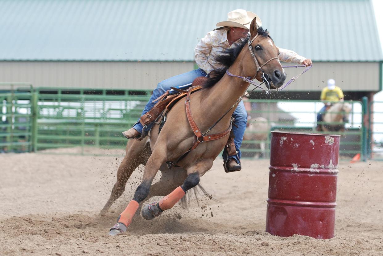 Young woman riding a beautiful horse in a barrel race competition during a rodeo.