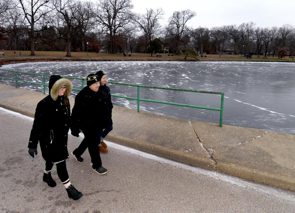 Keelin Staab of St. Louis, left, walks with her parents Robert Valenti, center, and Karen past the frozen lake in Washington Park Thursday Dec. 22, 2022.