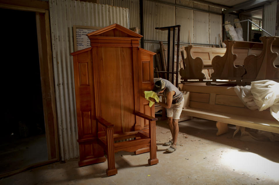 A worker dusts a wooden chair being made for Pope Francis that will be placed on an altar where he will give Mass on World Youths Day, at the studio of carpenter Hernan Guardia in Los Pozos, Panama, Saturday, Jan. 12, 2019. The Argentine pontiff will visit Panama Jan. 23-27. (AP Photo/Arnulfo Franco)