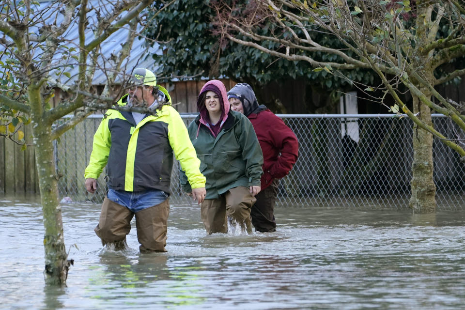 Dale Archer, left, leads his daughters Myranda and Krysten Archer through floodwater from their uncle's home Monday, Nov. 15, 2021, in Sedro-Woolley, Wash. The heavy rainfall of recent days brought major flooding of the Skagit River that is expected to continue into at least Monday evening. (AP Photo/Elaine Thompson)
