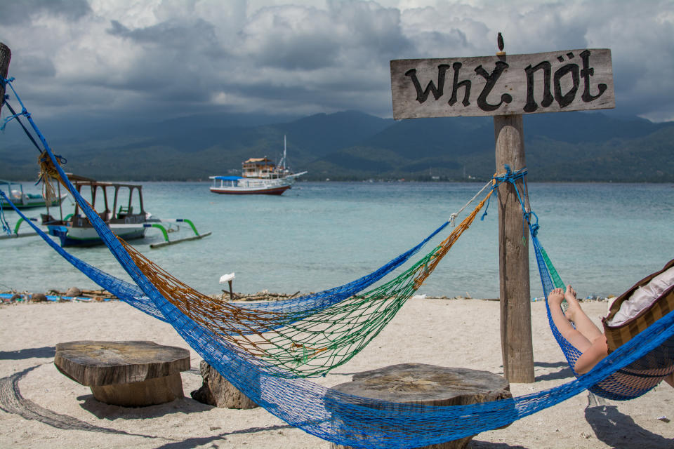 Hammocks in front of ocean with sign that says "Why Not"