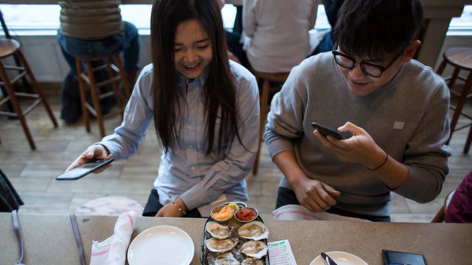 Diners take pictures of their assortment of oysters while dining at Eventide. - Derek Davis/Portland Press Herald/Getty Images