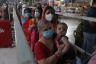 A woman holds a child as she stands in queue to offer prayers at Bhadrakali temple during Navratri, or festival of nine nights, in Ahmedabad, India, Saturday, Oct. 24, 2020. Weeks after India fully opened up from a harsh lockdown and began to modestly turn a corner by cutting new infections by near half, a Hindu festival season is raising fears that the disease could spoil the hard-won gains. Health experts worry the festivals can set off a whole new cascade of infections, further testing and straining India’s battered health care system. (AP Photo/Ajit Solanki)