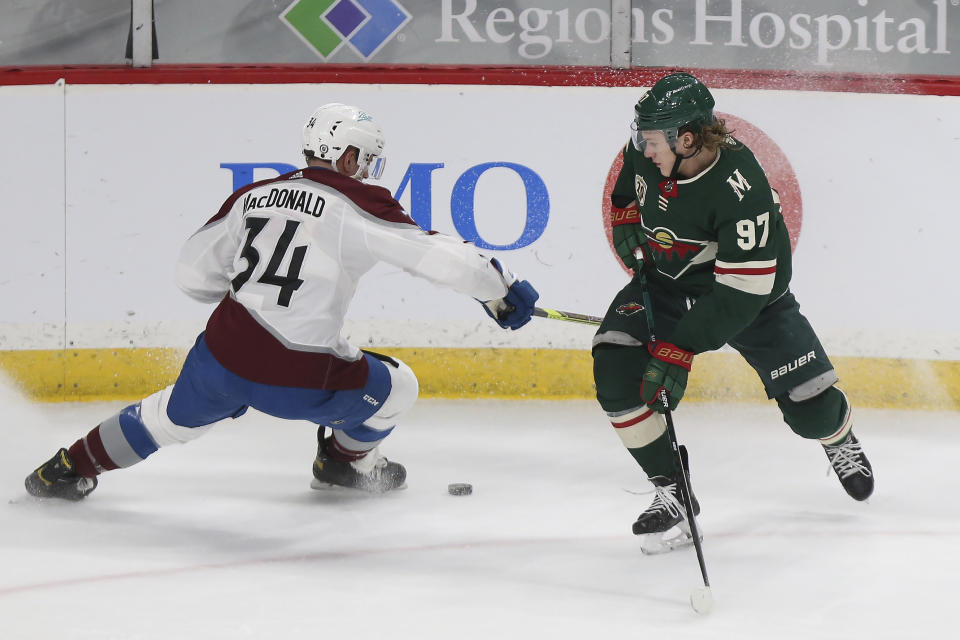 Minnesota Wild's Kirill Kaprizov (97) and Colorado Avalanche's Jacob MacDonald (34) go after the puck during the first period of an NHL hockey game Wednesday, April 7, 2021, in St. Paul, Minn. (AP Photo/Stacy Bengs)