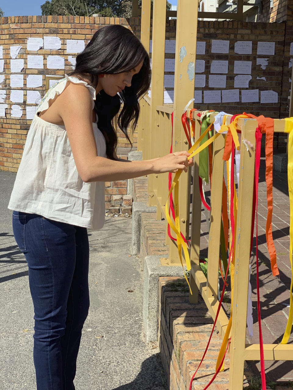 Photo by: KGC-178/STAR MAX/IPx 2019 9/28/19 Meghan, The Duchess of Sussex, ties a ribbon at the memorial to student Uyinene Mrwetyana at the post office where she was raped and murdered last month. A post on the official Instagram account of the Duke and Duchess of Sussex said "The Duke and Duchess had been following what had happened from afar and were both eager to learn more when they arrived in South Africa." These images were posted on @SussexRoyal today and supplied by the Royal Household.