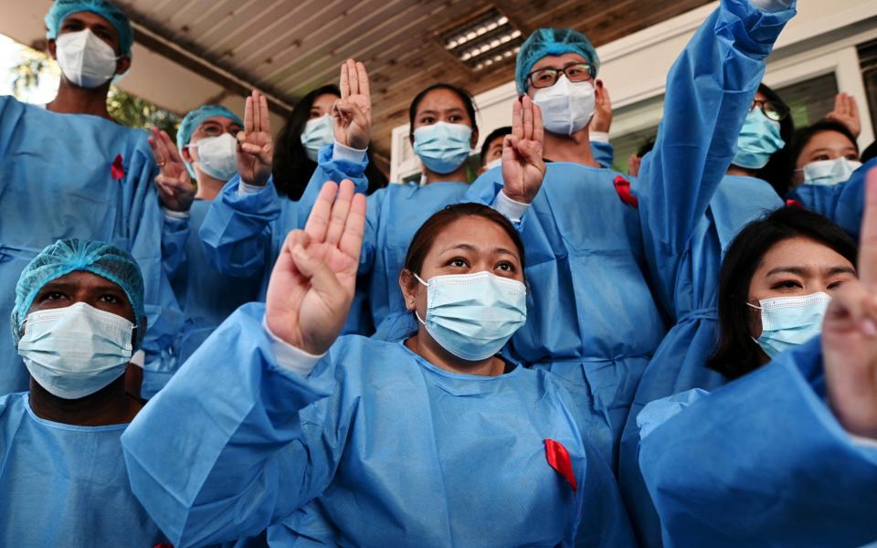 Medical workers wearing red ribbons pose during a protest against the coup - Reuters