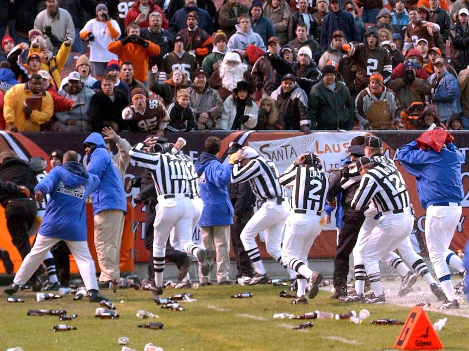 Game officials cover their heads and leave the field at Cleveland Browns Stadium while fans pelted them with plastic bottles and cups during their game agains the Jacksonville Jaguars on Sunday, Dec. 16, 2001