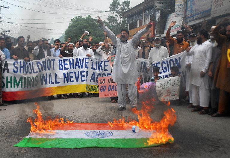 Indian Kashmiri refugees chant slogans beside a burning Indian flag during a protest against the visit of Prime Minister Narendra Modi to Kashmir, in Muzaffarabad on August 12, 2014