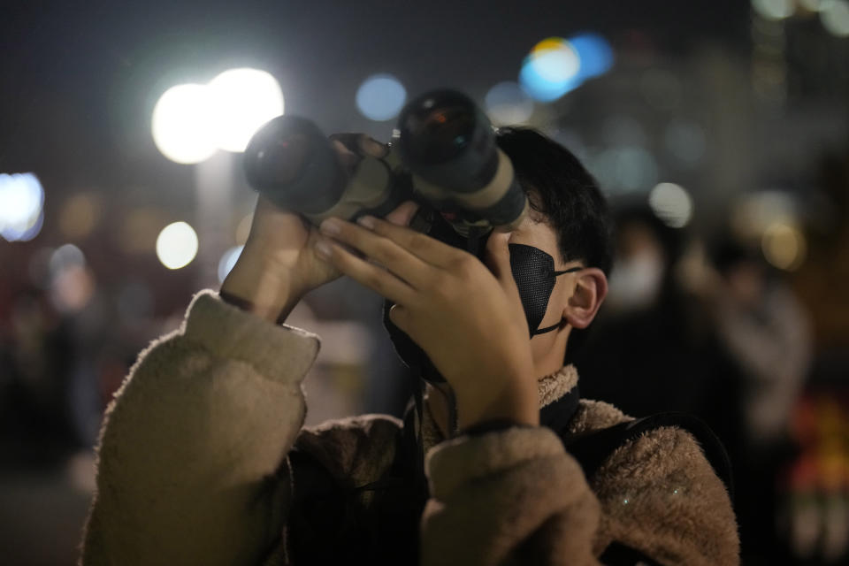 A man watches the moon through binoculars during a lunar eclipse in Goyang, South Korea, Tuesday, Nov. 8, 2022. (AP Photo/Lee Jin-man)