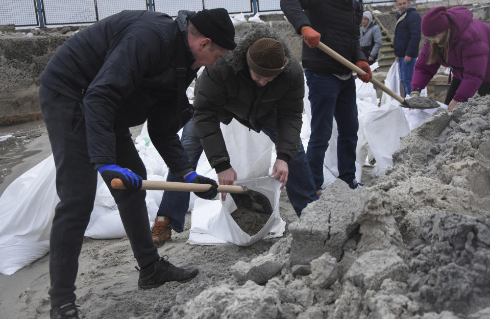 Volunteers at the beach scoop sand into sandbags for use in building barricades. 