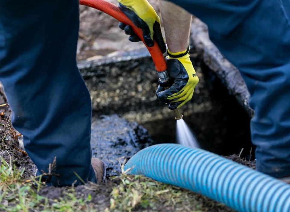Jeremy Langford, an employee at AA ARON Super Rooter, center, cleans out a septic tank at a home in Miami, Florida on Wednesday, September 30, 2020.