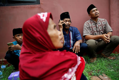 A man named Dai talks on the phone as he and and his family wait their turn to look for the body of his daughter at the police hospital in Jakarta, Indonesia October 27, 2017. REUTERS/Beawiharta