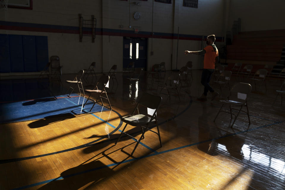 Chairs are spaced out as a volunteer prepares for a vaccination clinic to open in Central Falls, R.I., Saturday Feb. 20, 2021. Nearly a third of adults in the city have received at least one dose of vaccine, according to state data. Health officials say the city of about 20,000 has seen a marked drop in COVID-19 cases as a result. (AP Photo/David Goldman)