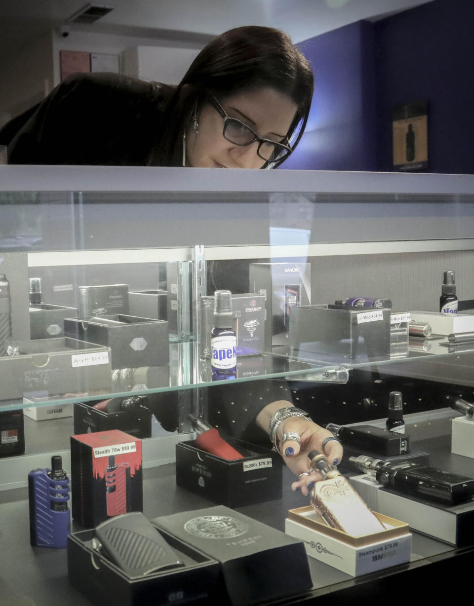 In this Tuesday, Oct. 8, 2019, photo Spike Babaian, owner of several Vape New York stores, works in her East Harlem store in New York. Sales at small businesses that sell vaping products have plunged since August, when reports of vaping-related illnesses and deaths began. “We can never undo the government going on the news and saying it’s not safe to vape. The damage has been done,” says Babaian, who has been in business for eight years. (AP Photo/Bebeto Matthews)