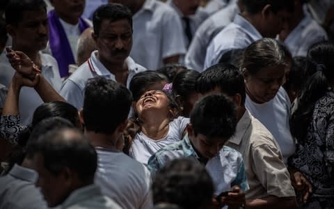 A woman cries as a coffin is buried during a mass burial near St Sebastian Church on April 23, 2019 in Negombo, Sri Lanka - Credit: Getty