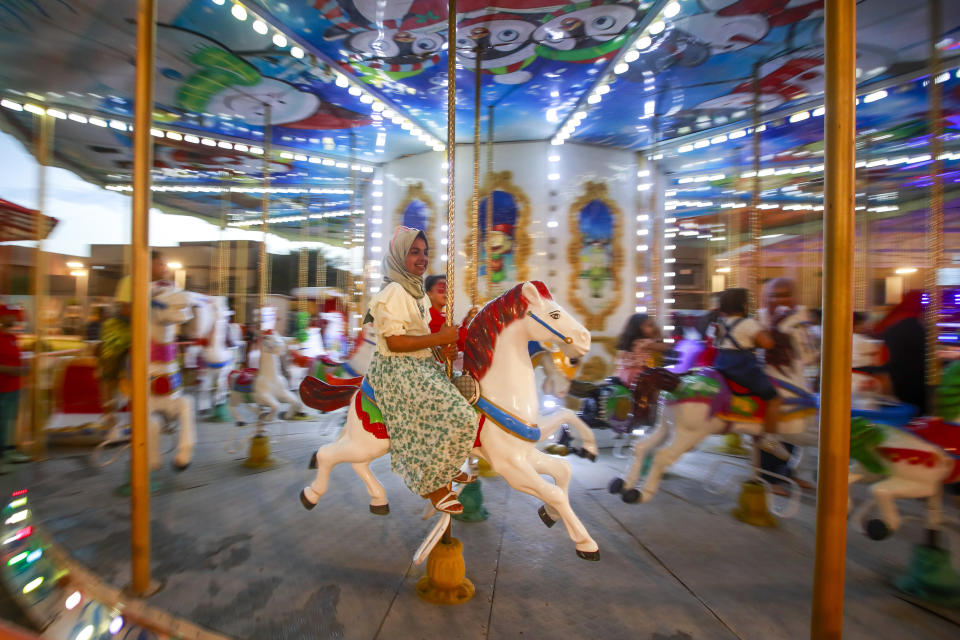 An Iraqi girl smiles during a ride in an amusement park in Hila, Iraq, Sunday, April 23, 2023 during Eid al-Fitr holiday that marks the end of the holy Islamic month of Ramadan. (AP Photo/Anmar Khalil)