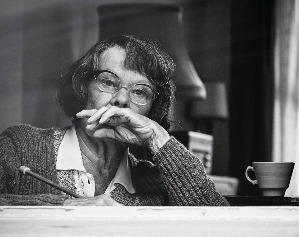 Judi Dench sits at a table