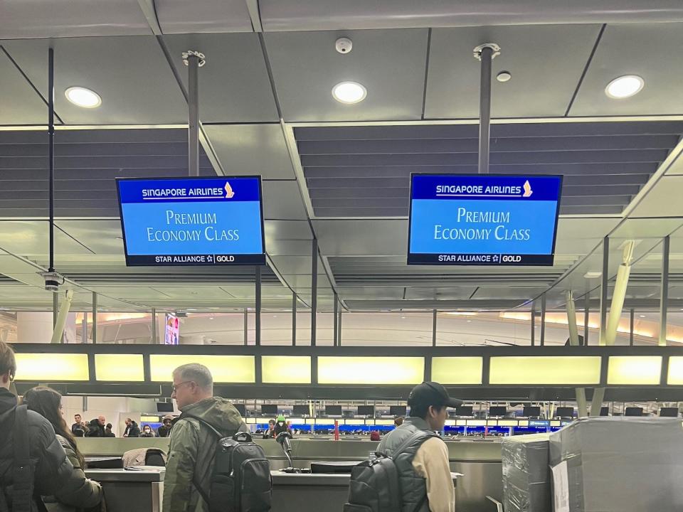 The dedicated line for premium economy. Passengers stand around waiting to check in luggage.