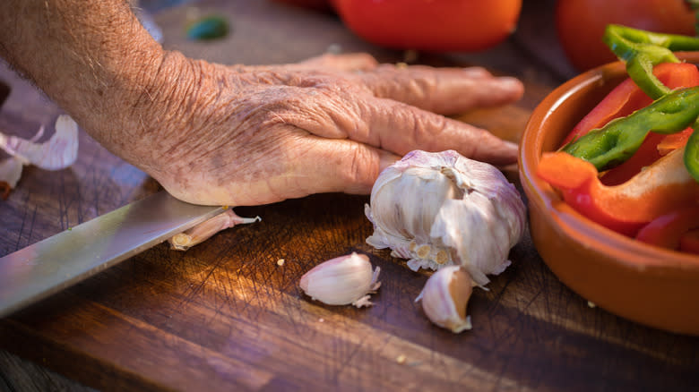 Person crushing garlic with knife