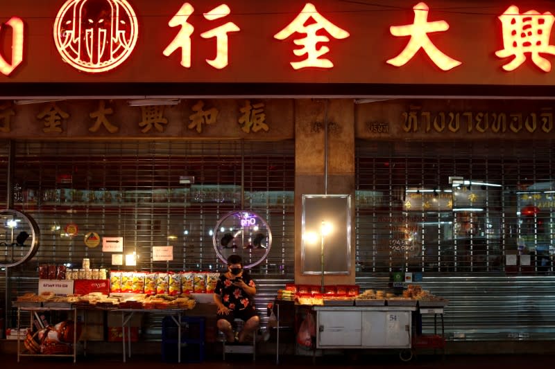 A woman wearing a mask waits for customers at an empty food stall during the coronavirus disease (COVID-19) outbreak, in Chinatown, Bangkok