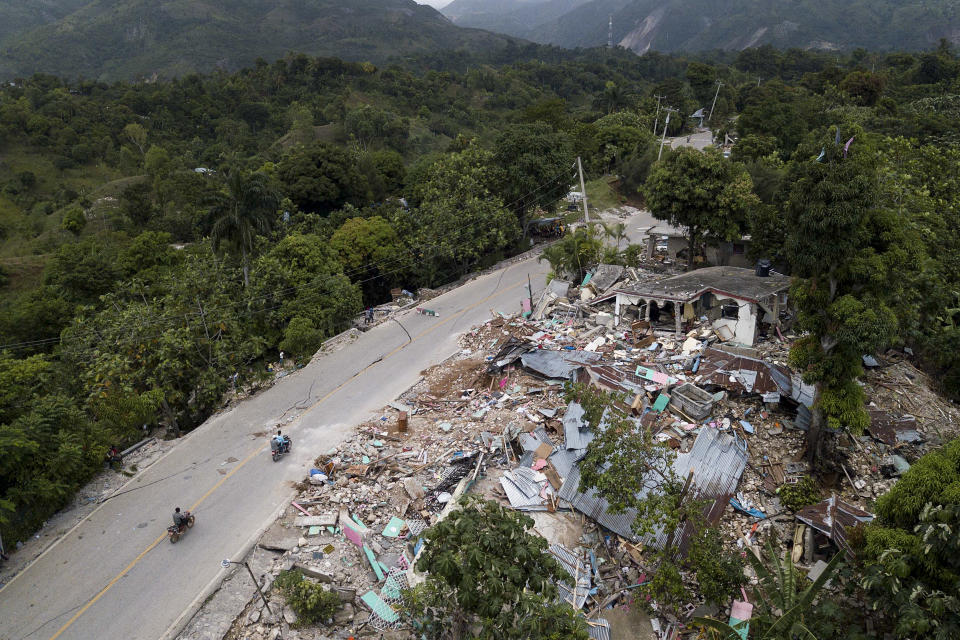 Homes lay in ruins along an earthquake-damaged road in Rampe, Haiti, Wednesday, Aug. 18, 2021, four days after 7.2-magnitude earthquake hit the southwestern part of the country. (AP Photo/Matias Delacroix)