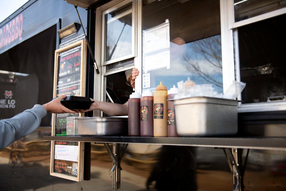 Brandon Evans serves lunch from Rad Dad's BBQ at Scuffletown Food Truck Park in Simpsonville on Friday, Jan. 5, 2024.