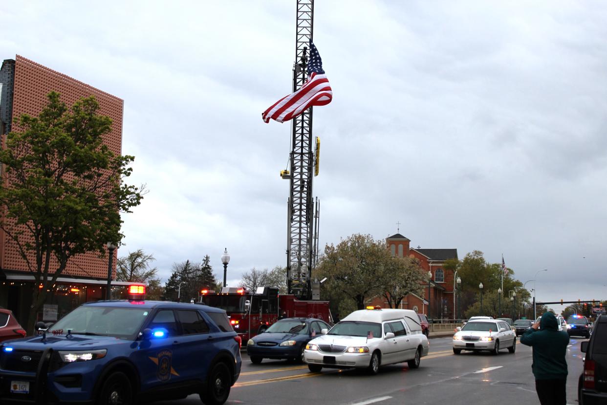 The American flag and a firefighter’s boot hang from the city of Monroe Fire Department’s aerial ladder as members of the community gathered Tuesday afternoon May 2, 2023, in downtown Monroe to honor late Army Sgt. Douglas Simpson III of Dundee.