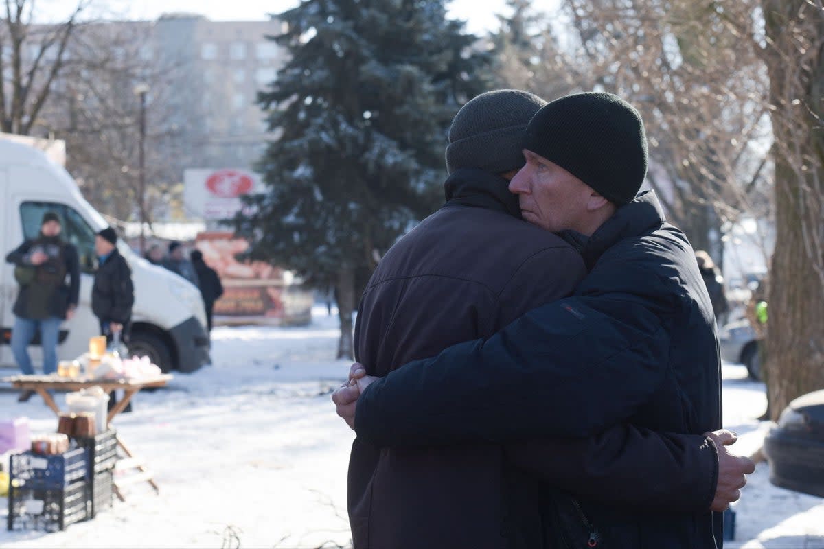 Two men embrace each other at the site of a missile strike in Donetsk (AFP via Getty Images)