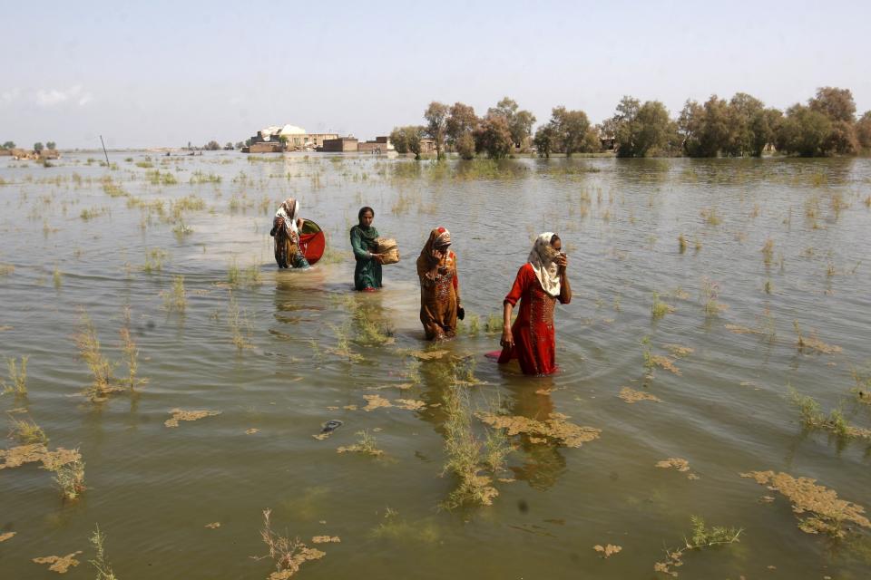 FILE - Women wade through floodwaters as they take refuge in Shikarpur district of Sindh Province, of Pakistan, Sep. 2, 2022. The flooding in Pakistan killed at least 1,700 people, destroyed millions of homes, wiped out swathes of farmland, and caused billions of dollars in economic losses. (AP Photo/Fareed Khan)