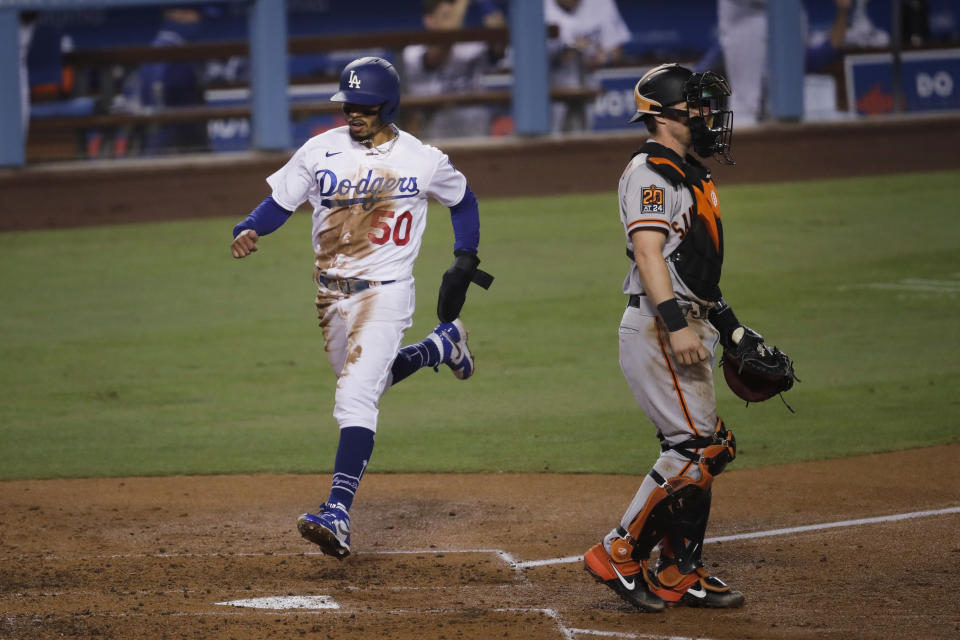 Los Angeles Dodgers' Mookie Betts, left, scores on a single by Cody Bellinger as San Francisco Giants catcher Tyler Heineman stands in front of the plate during the third inning of a baseball game Sunday, July 26, 2020, in Los Angeles. (AP Photo/Jae C. Hong)