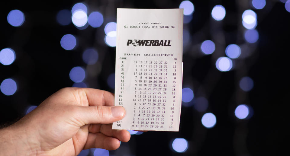 Pictured is a man's hand holding a Powerball Super Quickpick ticket. 