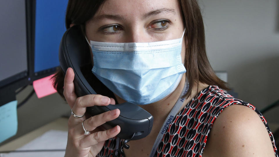 In this Tuesday, May 19, 2020, photo, health investigator Mackenzie Bray sits in her office at the Salt Lake County Health Department in Salt Lake City. Bray normally works to track contacts for people with sexually transmitted diseases, but she was re-assigned during the coronavirus pandemic. She is now one of 130 people at this county health department assigned to track down COVID-19 cases in Utah's urban center around Salt Lake City. The investigators, many of them nurses, each juggle 30 to 40 cases that can include a total of several hundred people. (AP Photo/Rick Bowmer)