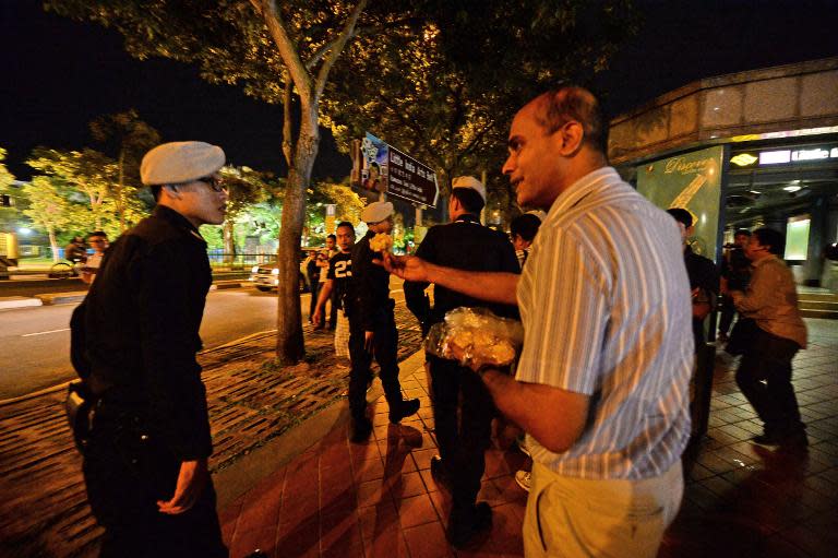 Singaporean activist Vincent Wijeysingha (R) hands out yellow flowers to a police officer patrolling outside the train station in the Little India district of Singapore on December 15, 2013