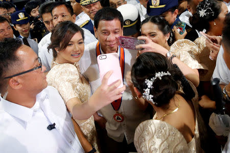 Philippines President Rodrigo Duterte is having his pictures taken with three girls as they attend the ceremony marking the anniversary of the Philippines Coast Guard in Manila, Philippines, October 12, 2016. REUTERS/Damir Sagolj/File Photo