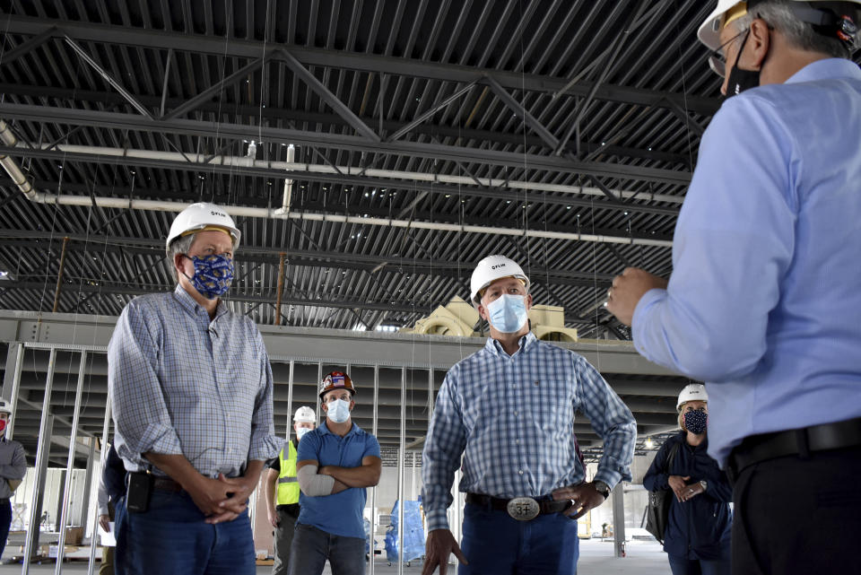 Republicans U.S. Sen. Steve Daines, left, and Rep. Greg Gianforte listen to a representative of FLIR Systems describe the technology company's new facility under construction on Wednesday, Sept. 2, 2020 in Bozeman, Mont. After working together in the corporate world the duo have risen in tandem to political influence. (AP Photo/Matthew Brown)